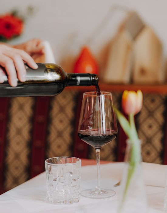 Rotwein wird ins Glas eingeschenkt